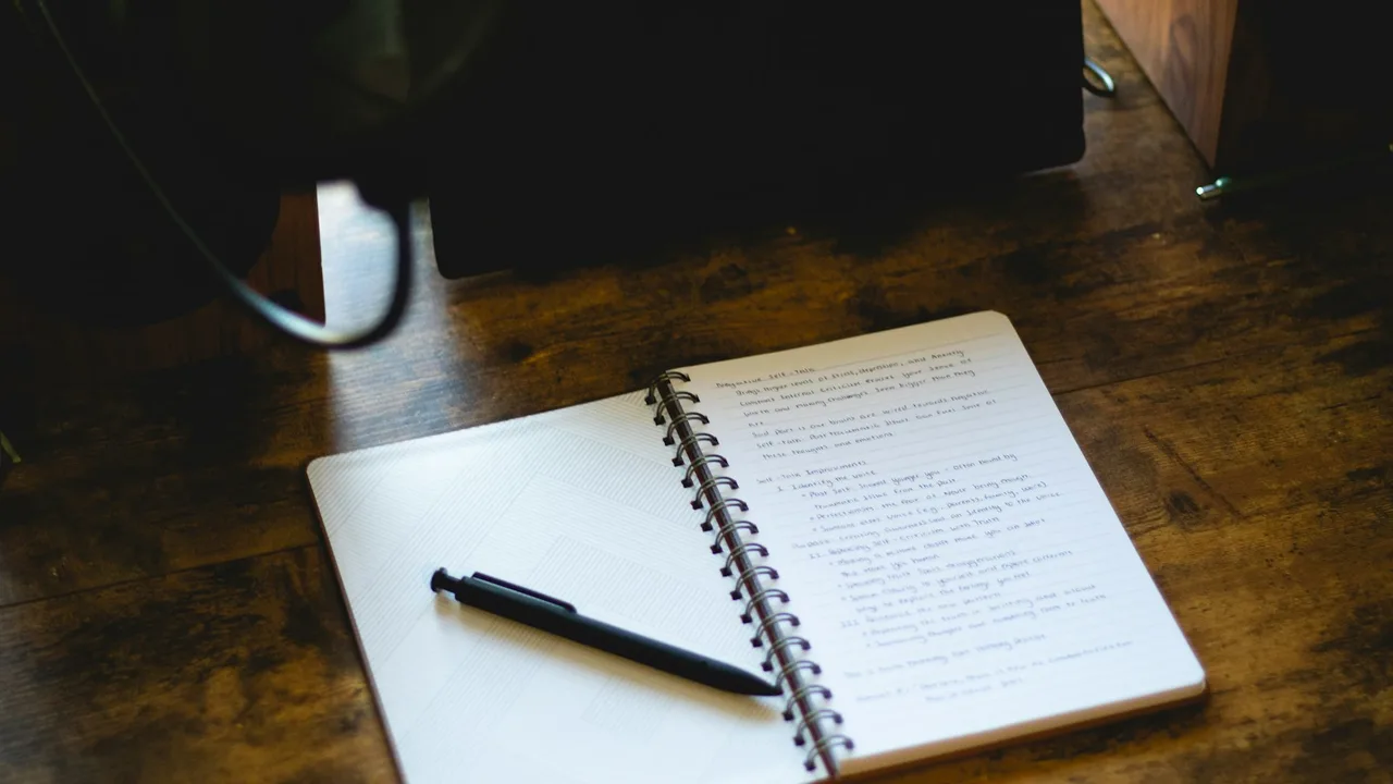 An open notebook and pen on a wooden desk