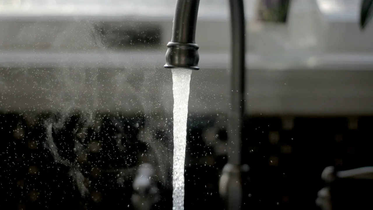 Water flowing from a dark kitchen faucet