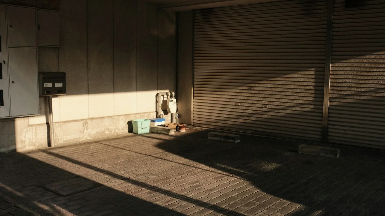 Closed roll-up garage door with sunlight across the foreground